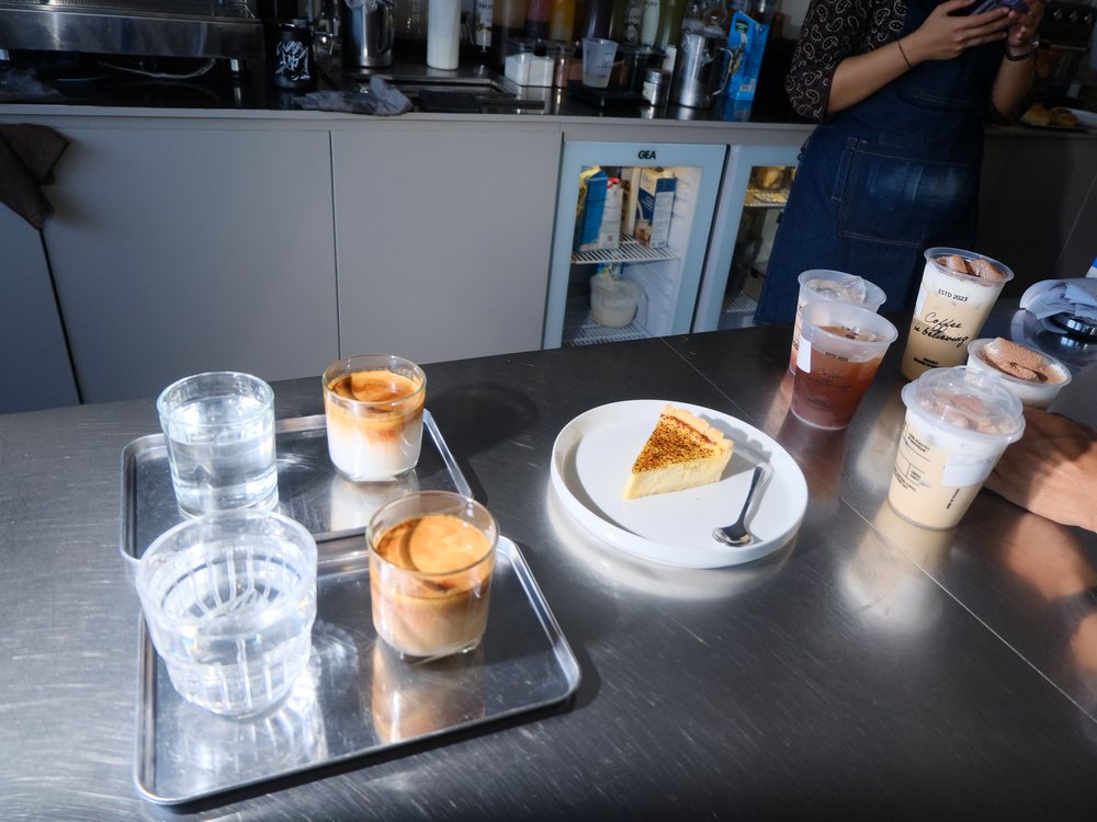 Deretan kopi susu, es kopi dan cheesecake di meja bar Roket